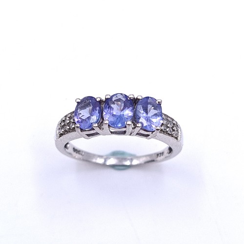 552 - A three stone tanzanite ring with diamond cluster mount set in sterling silver. Size - K. Weight - 1... 