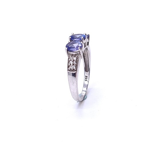 552 - A three stone tanzanite ring with diamond cluster mount set in sterling silver. Size - K. Weight - 1... 