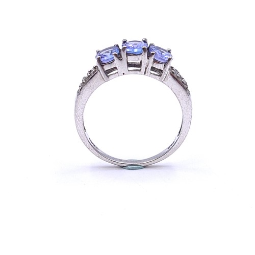 552 - A three stone tanzanite ring with diamond cluster mount set in sterling silver. Size - K. Weight - 1... 