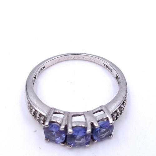 552 - A three stone tanzanite ring with diamond cluster mount set in sterling silver. Size - K. Weight - 1... 