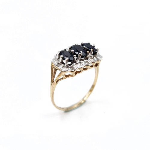 2 - Star Lot : A nice example of a nine carat gold three stone sapphire ring with diamond cluster surrou... 