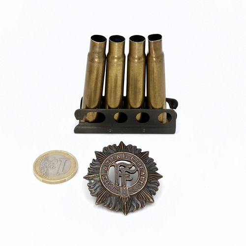 33 - A vintage Irish military cap badge with a clip of spent bullets.