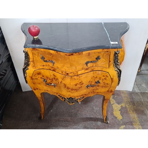 1231 - Star Lot A handsome Burl wood bombe chest with black marble top and ornate brass detailing, featurin... 