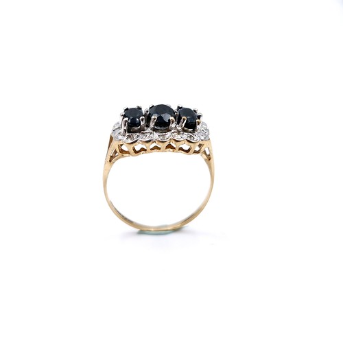 2 - Star Lot : A nice example of a nine carat gold three stone sapphire ring with diamond cluster surrou... 