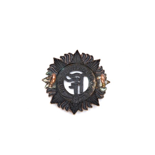 33 - A vintage Irish military cap badge with a clip of spent bullets.