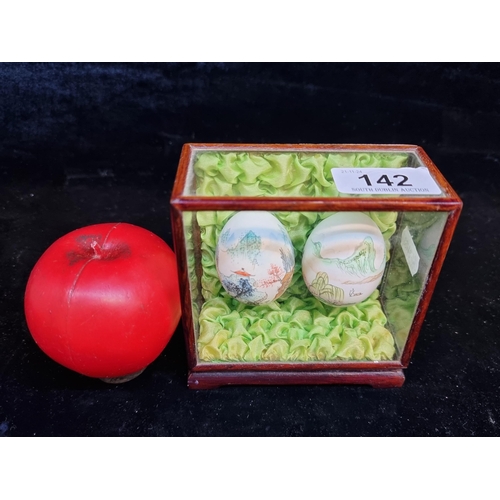 142 - A pair of hand painted Chinese bird eggs mounted in a glass and wood display case.