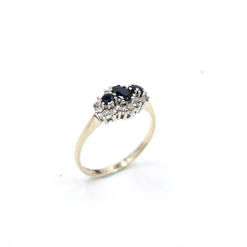 56 - Star Lot : A pretty three stone sapphire ring with diamond cluster mount. Size - P 1/2. Weight - 2.1... 