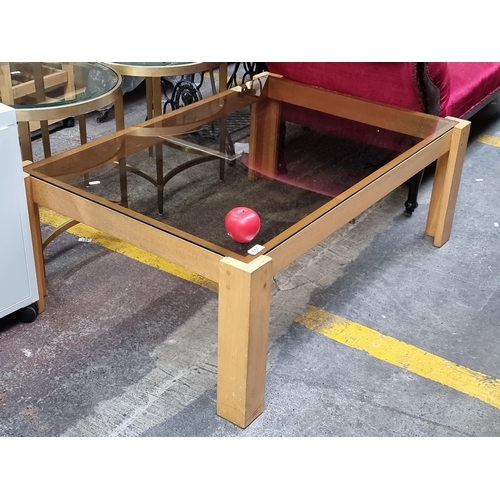 651 - A solid wood and smoked class coffee table. Great 1980s sleek design.