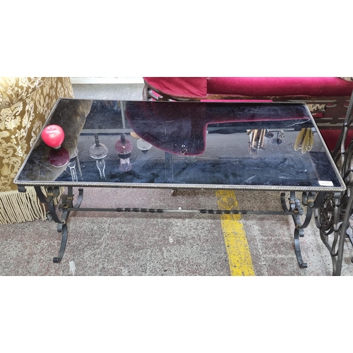 658 - A stunning glass top wrought iron coffee table featuring beautifully intricately crafted legs.