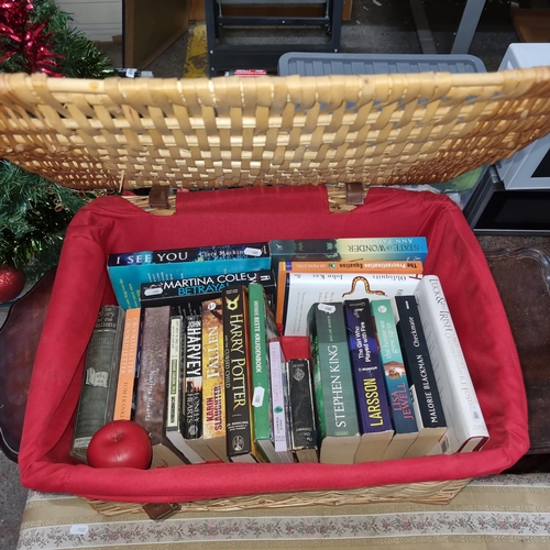 673 - A large woven lined hamper basket containing a selection of books including titles such as Stephen K... 