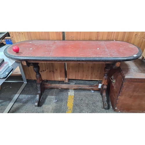 718 - Victorian mahogany writing table with carved trestle legs and inset leather top.