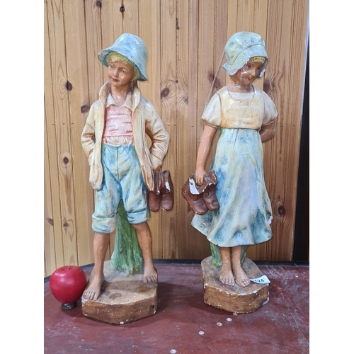 724 - Hand-painted large plaster figurines of a boy and girl, each holding shoes. Vintage style, from mid-... 