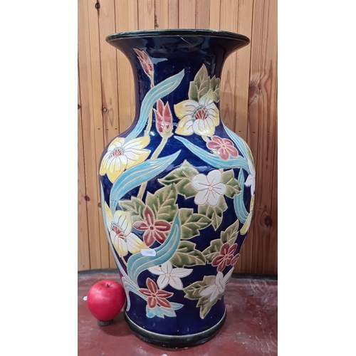 725 - Large ceramic vase with vibrant floral motifs on a deep blue background, featuring an intricate hand... 