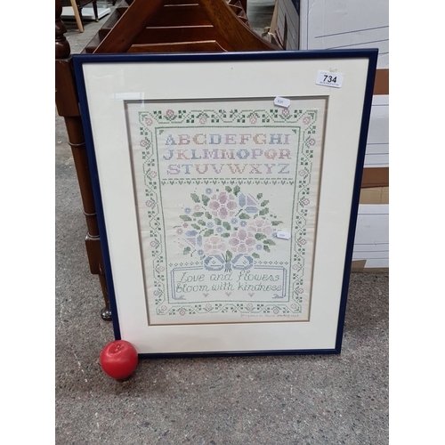 734 - Framed cross-stitch sampler featuring alphabet and floral design. Includes the inscription 