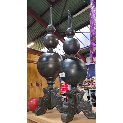 781 - Pair of large black finials with ornate bases, featuring a tiered spherical design and pointed tops.... 