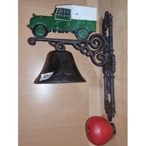 805 - Cast iron wall-mounted bell features a green and white car motif, decorative scrollwork, and a red a... 