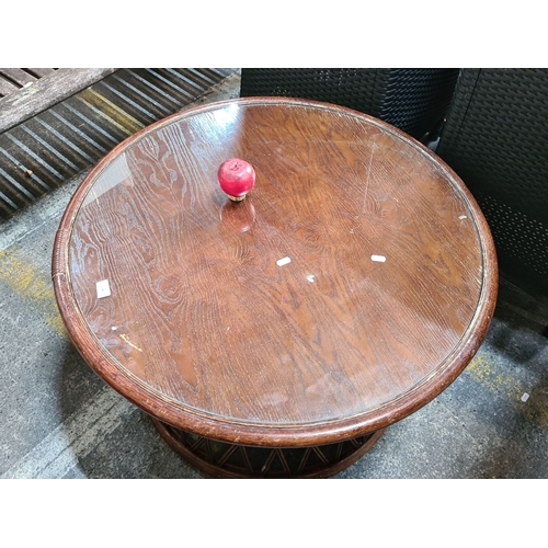 1136 - A Round glass-topped rattan coffee table with wood veneer surface.