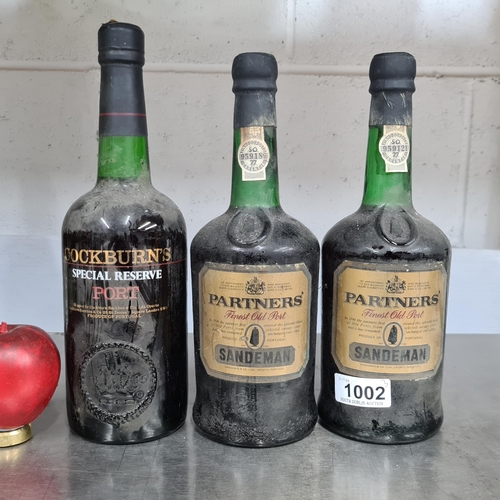 1002 - Three bottles of vintage Port including two 70cl bottles of Partners Sandeman Finest Old Port and a ... 