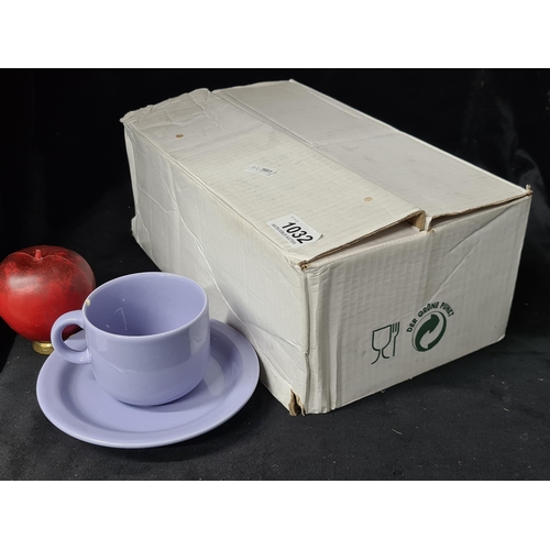 1032 - A box containing ceramic cups and saucers. Includes six cups and six saucers. Features a soft lilac ... 