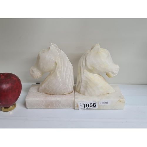 1058 - A pair of carved marble bookends in the form of horse heads.