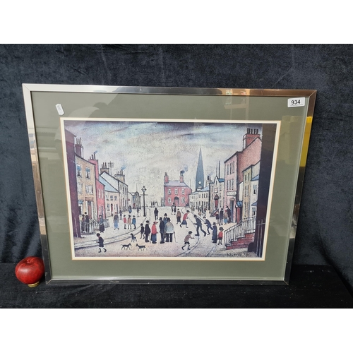 934 - A high quality print 'L.S Lowry' painting titled ' A Village Square'. Housed in a chrome frame behin... 