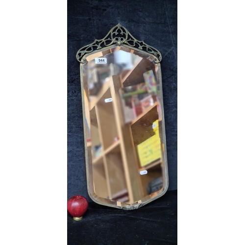 944 - An ornate vintage metal framed wall hanging mirror with spiral scroll detailing. 
MM: 31cm x 67cm.