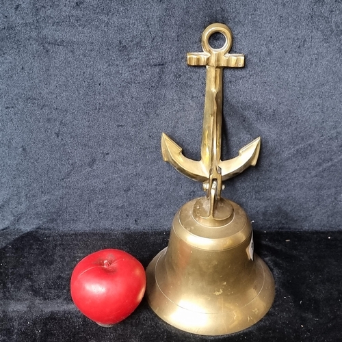 956 - A nautical / maritime brass wall hanging bell features an anchor. Missing the clapper.