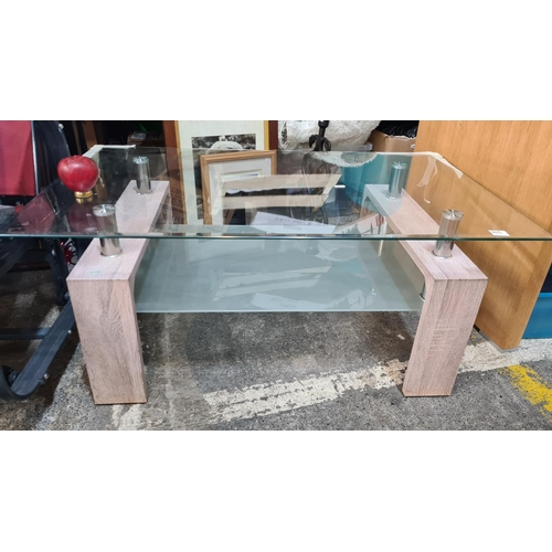 1169 - A handsome glass coffee table with oak legs. Includes tempered glass storage shelf.