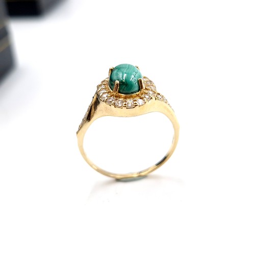 548 - A nine carat gold plated malachite cabochon stone ring with gem set mount and surround. Size - W. We... 