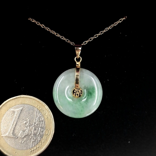 32 - Star Lot : A circular jade pendant with gold chain marked 14K. Length of chain - 44 cms. Total weigh... 