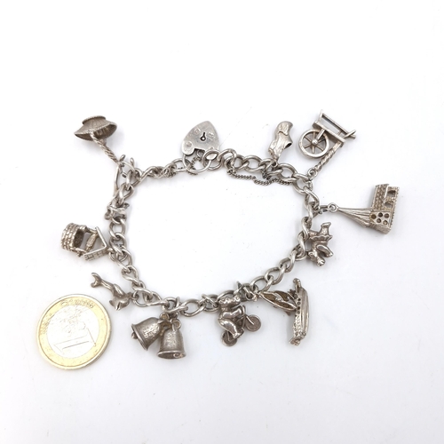 38 - A sterling silver charm bracelet together with 12 charms, silver padlock clasp and safety chain. Wei... 