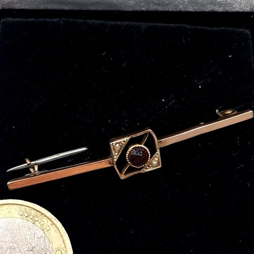 560 - A nine carat gold garnet stone and seed pearl brooch. Length - 5 cms. Weight - 1.35 grams. Pin intac... 