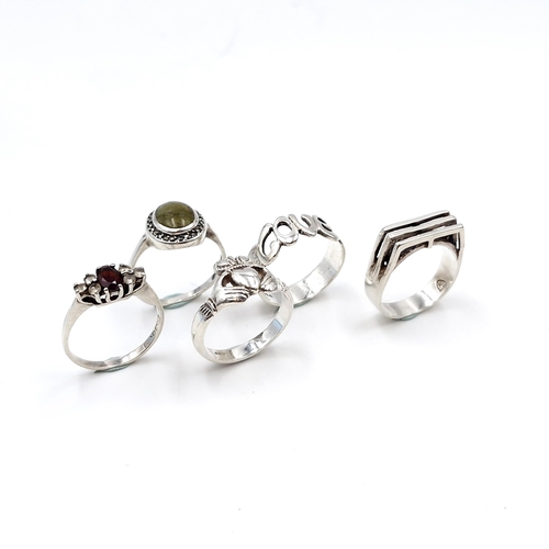 992 - A collection of five Irish sterling silver rings including two gem set examples featuring a garnet s... 