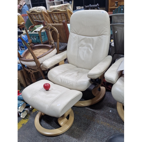 752 - Cream leather recliner and footstool with wood base, featuring plush cushioning.