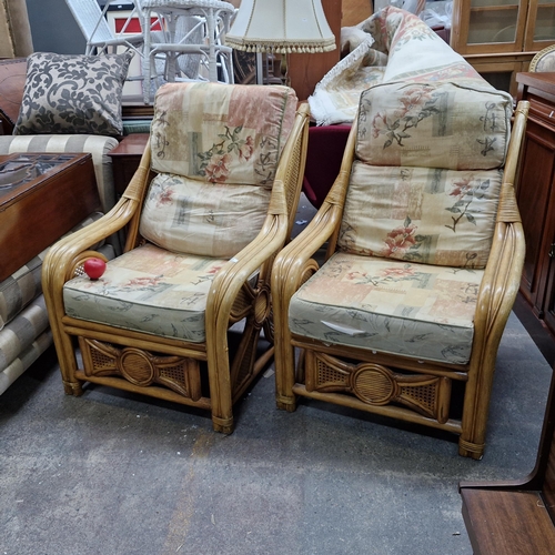 707 - A pair of cane rattan armchairs with comfortable foam padded seats and flower design to side rattan.