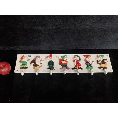 229 - A charming cast iron seven tier coat/hat rack depicting the characterful seven dwarfs.
