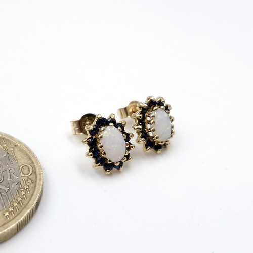 12 - Star Lot : A pair of nine carat gold sapphire and opal stud earrings. Weight - 1.39 grams.