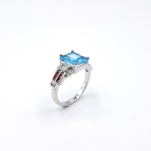 22 - A good example of an blue topaz stone ring with garnet accents set in sterling silver. Size - R. Wei... 