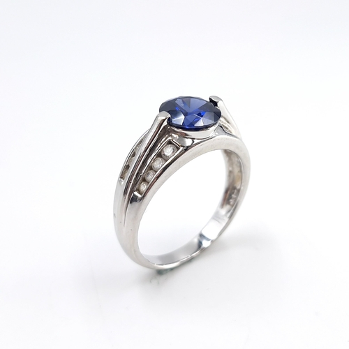 24 - A blue centre stone cubic zirconia sterling silver ring. Size - R. Weight - 4.56 grams.