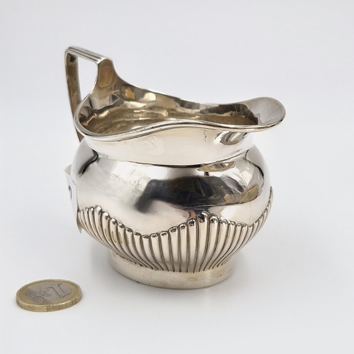 42 - A pretty sterling silver cream jug hallmarked London featuring attractive ribbed body. Length - 11 c... 