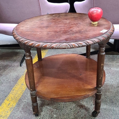 406 - Vintage round walnut tea table, featuring elegantly carved edge and dual-tier design with castors.