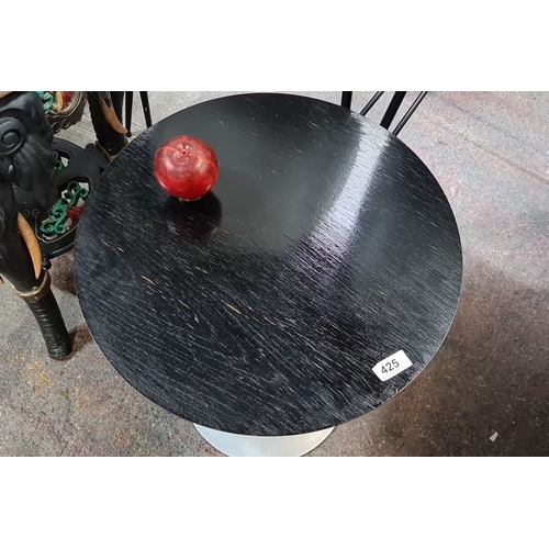 425 - A vintage round side table with a sleek metal base and black wood top.