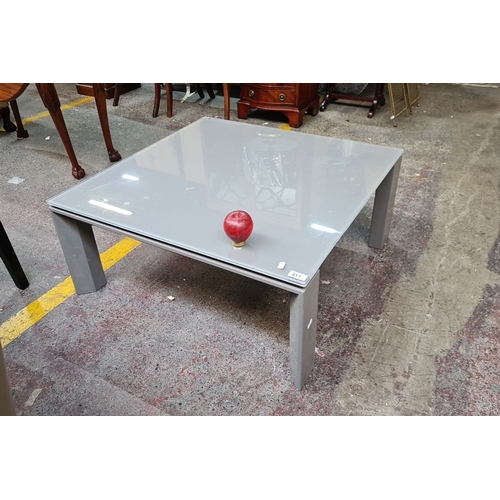 998 - Coffee table with glass top and metal legs, 90 cm square. It has a glossy surface and sturdy build.
... 