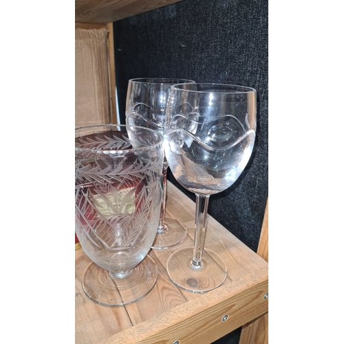 1070 - A set of two large matched crystal goblets, two etched with swirling patterns, with one with leaf mo... 