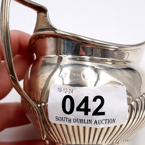 42 - A pretty sterling silver cream jug hallmarked London featuring attractive ribbed body. Length - 11 c... 