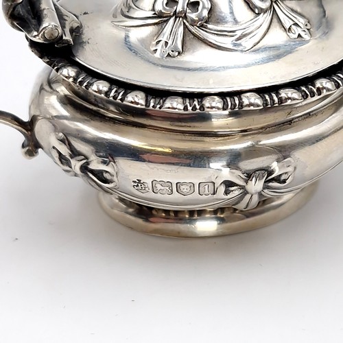 592 - A sterling silver mustard pot hallmarked London set with repousse design. Pot has bristol blue glass... 