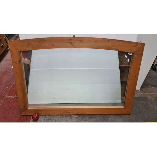 272 - A large pine curved over mantle mirror featuring contemporary design. Approc 120cm x90cm good qualit... 