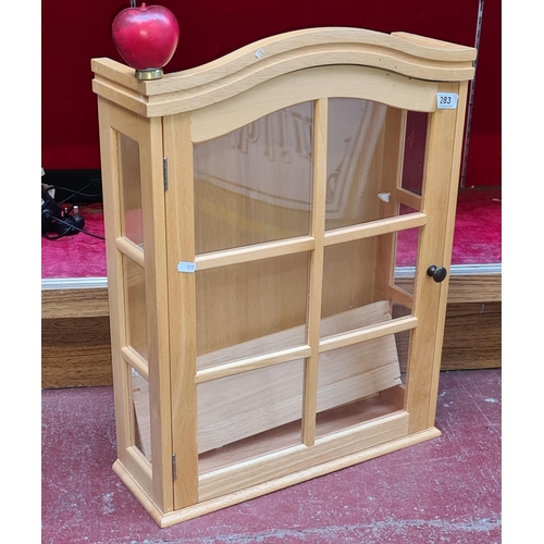 283 - A glazed front beech wood cabinet with two internal shelves.