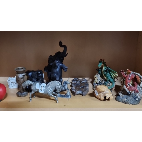 1002 - Eclectic figurine collection includes metallic horse, mythical creatures, and wooden sculptures.
Pre... 