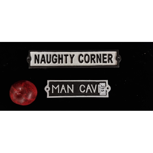 215 - Two humorous cast metal wall plaques reading 'Man Cave' and ' Naughty Corner'.